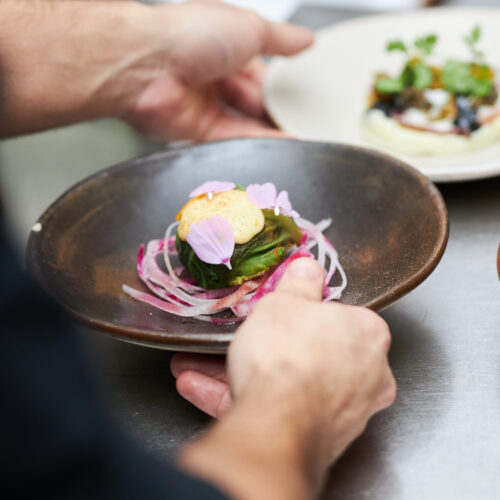 Assiette bistronomique dressée chez Bleu Canard à Lille avec légumes, sauce et fleurs comestibles