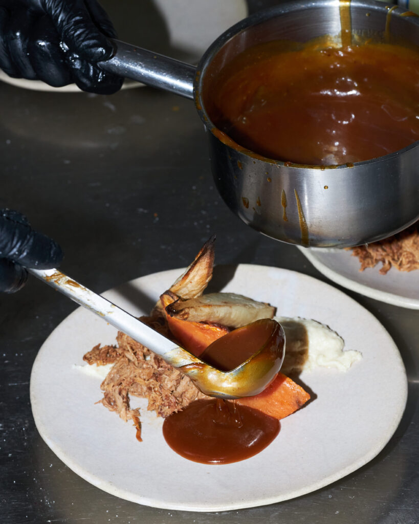 Dressage d’un plat en cuisine chez Bleu Canard à Lille avec viande, légumes rôtis et sauce