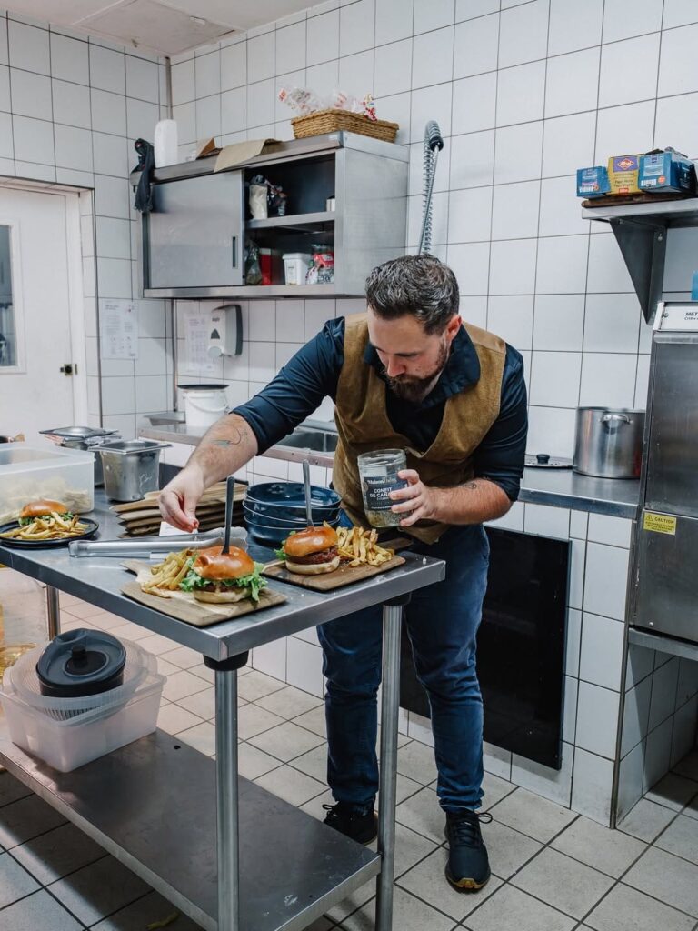 Chef qui prépare les burgers d'un foodtruck qui sillone sur Momères, Dours, Trie sur Baïse, Aureilhan, Luc et Odos