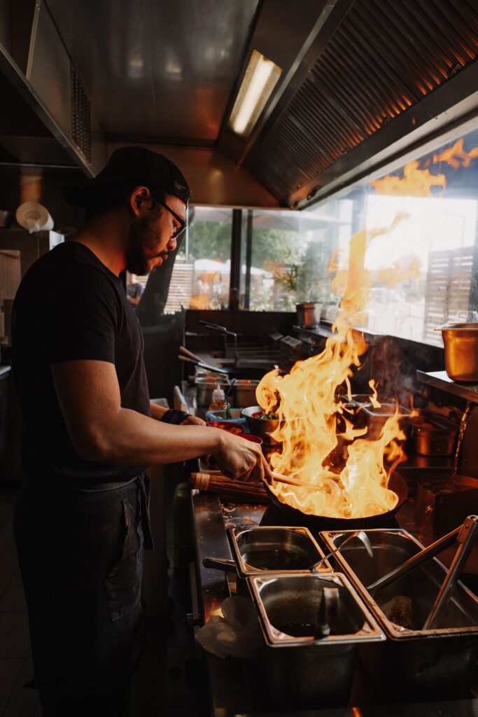 Cuisinier jouant avec le feu d'un restaurant de type cuisine thaï à Tarbes, près de Pau