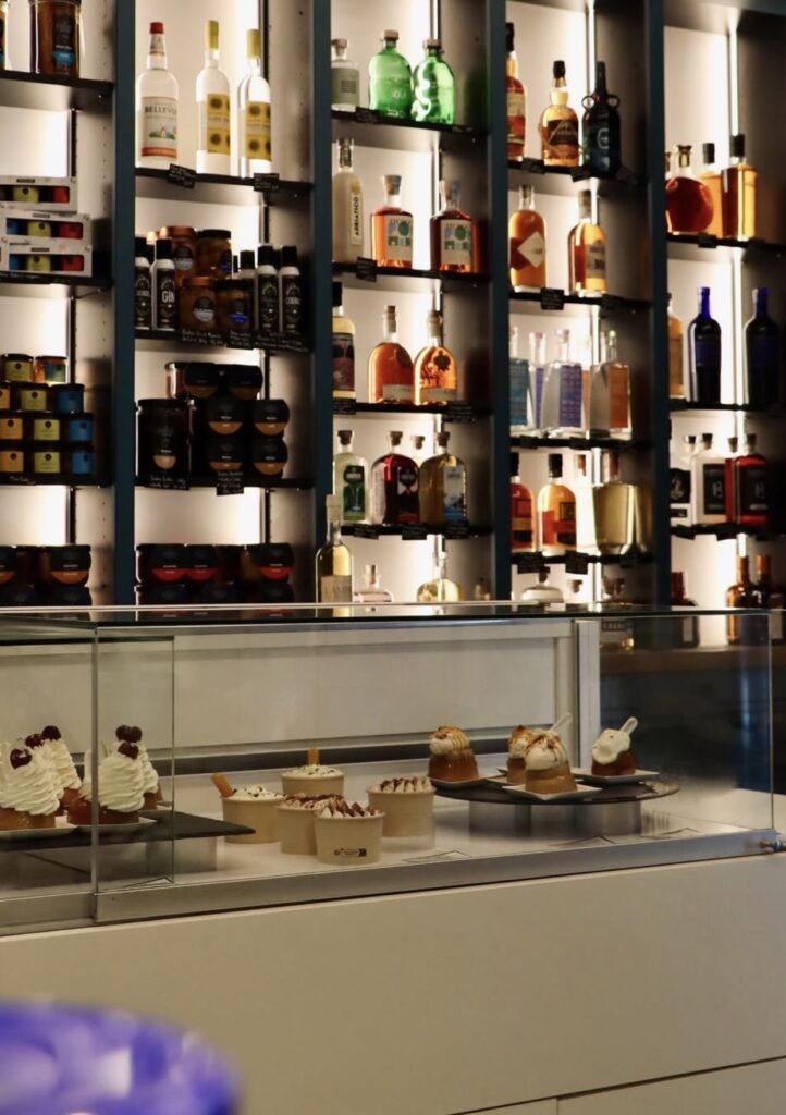 Des babas façonnés à la main, respectant les gestes artisanaux, présentés avec des bouteilles de rhum en arrière-plan. L'épicerie des Babas, Saint-Malo.