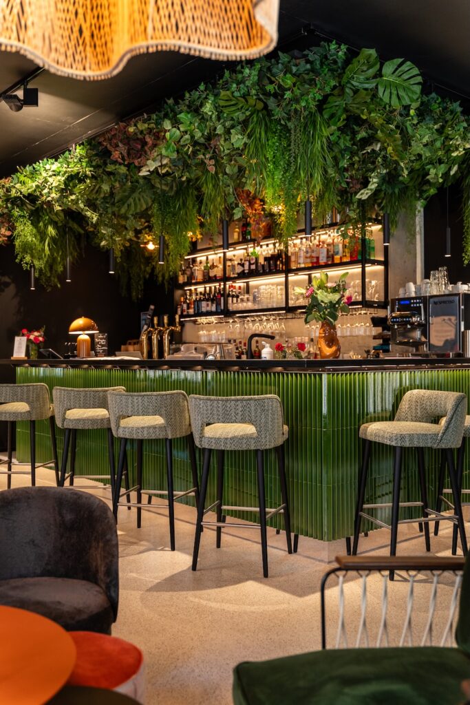 Bar moderne avec chaises hautes et plantes à Pastia Mia à Saint-Malo.