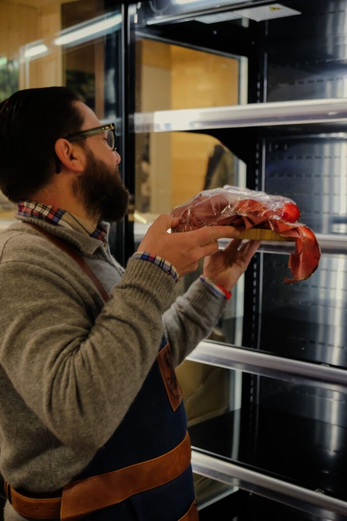 Epicier qui sort un produit de l'étagère de l'épicerie Chez Loulou à Besançon