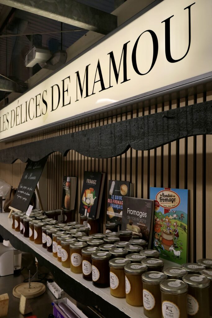 Étagère de confitures et enseigne à la fromagerie Les Délices de Mamou au marché de La Teste-de-Buch.