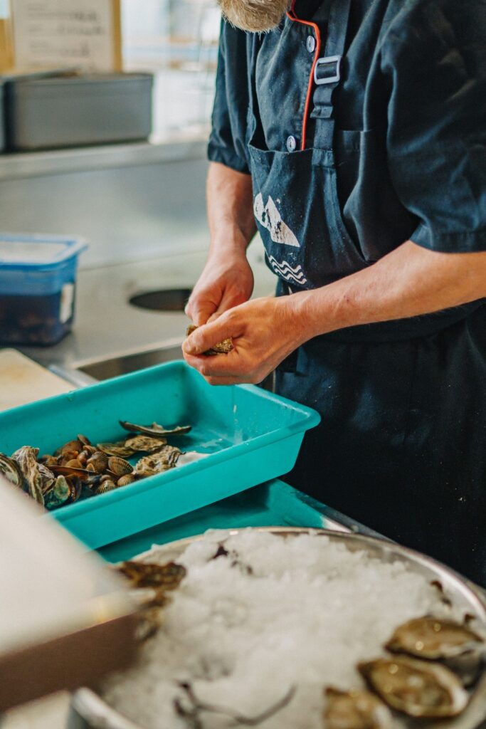 Un chef qui ouvre des huîtres dans la cuisine d'un restaurant de type cuisine française à Pau, près de Tarbes