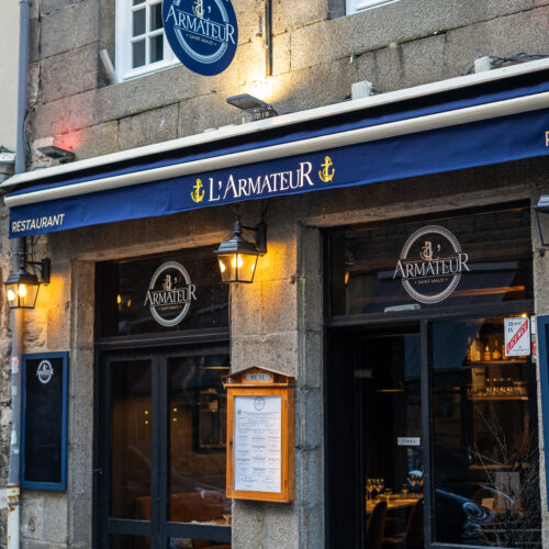 Façade en pierre avec logo bleu du restaurant L'Amateur à Saint-Malo.