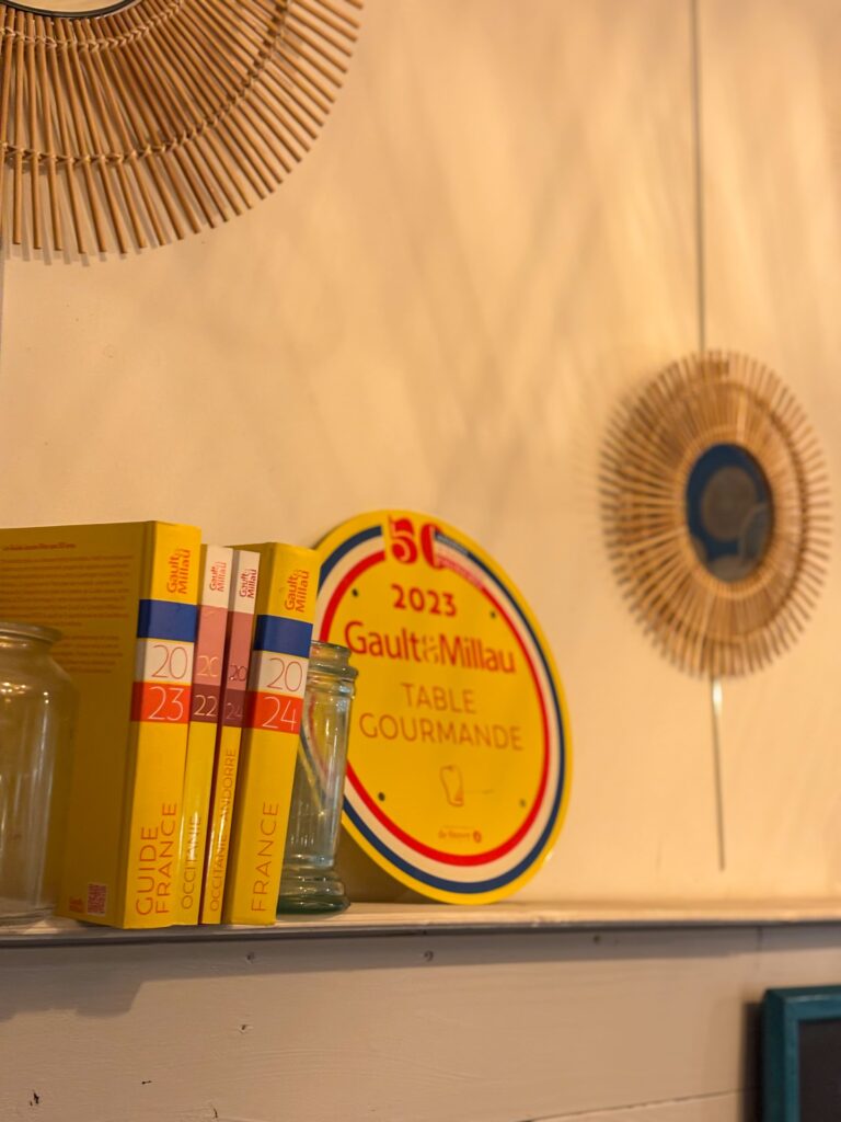 Une plaque Gault et Millau posée sur une étagère au restaurant La Table des Poètes