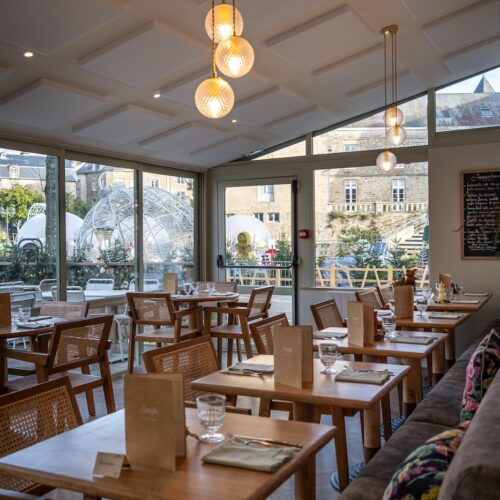 Salle lumineuse avec grandes baies vitrées et mobilier en bois à la Crêperie Suzette à Dinan.