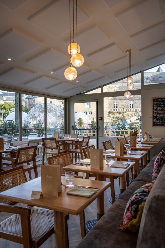 Salle lumineuse avec grandes baies vitrées et mobilier en bois à la Crêperie Suzette à Dinan.
