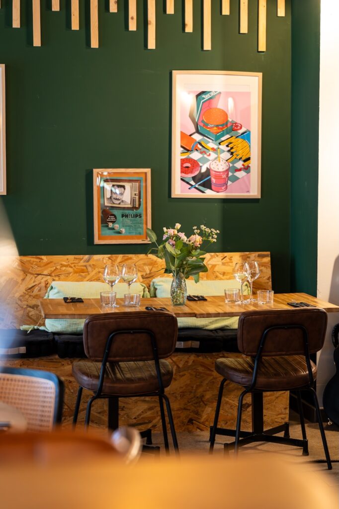 Salle intérieure lumineuse avec murs verts et cadres colorés à L'Accalmie à Beaussais-sur-Mer.