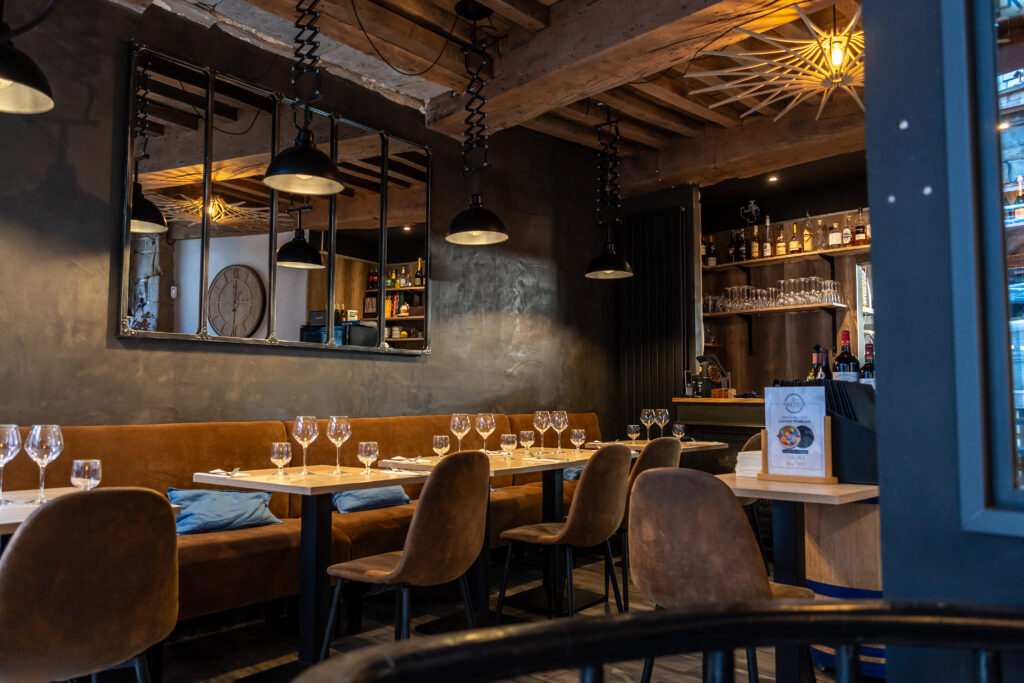Salle au style industriel avec lumière tamisée et sièges marron à L'Amateur à Saint-Malo.