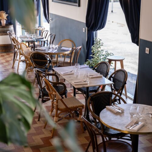 Salle intérieur avec tables dressées et rideaux au Riva Café à Saint-Malo.