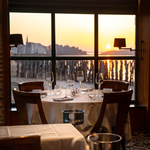 Table dressée face à la mer et au coucher de soleil à la Brasserie du Sillon à Saint-Malo.