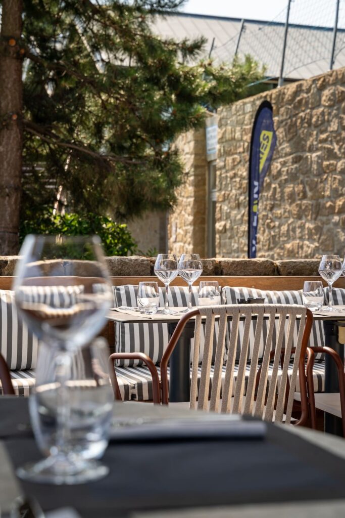 Terrasse ensoleillée avec coussins marinières aux Voiles de Solidor à Saint-Malo.
