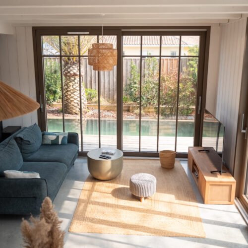 Salon et extérieurs de la Villa du Lac, proposée par Les Cocons du Bassin. Une villa en bois familiale à proximité du lac de Cazaux.