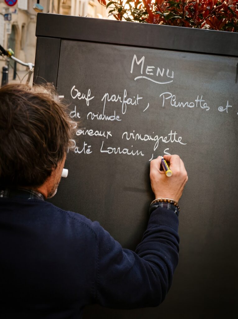 Le gérant du Hibou Saint Michel écrit le menu du jour