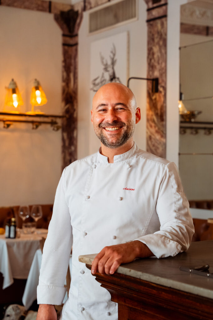 Le Chef Antoine Gandon débout souriant dans son restaurant