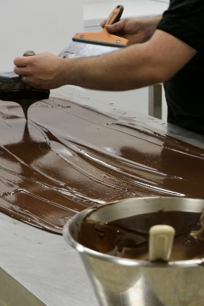 Tablage du chocolat pour la réalisation de la pinasse gourmande, à la pâtisserie, salon de thé et chocolaterie Plume à Arcachon.